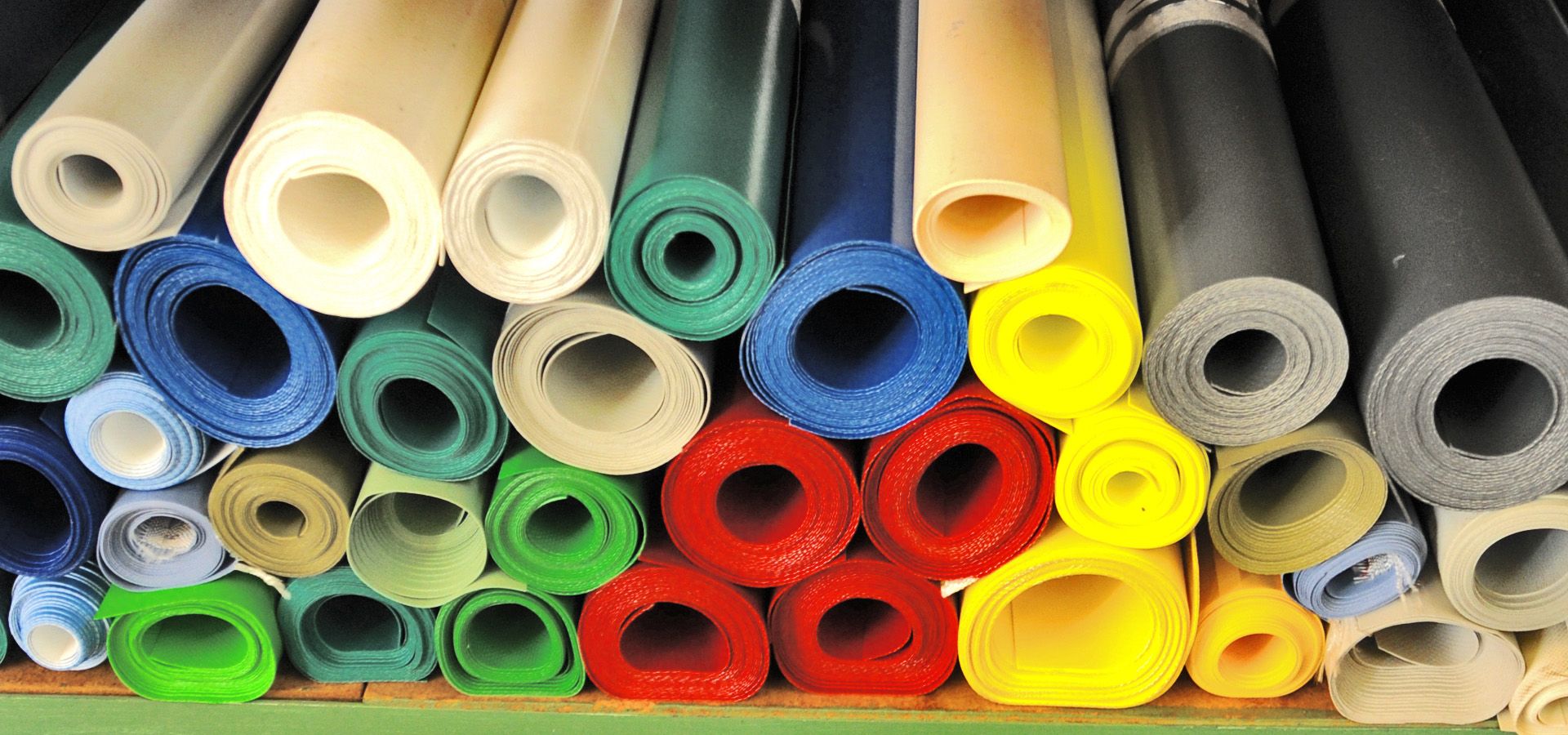 Bild von zahlreichen aufgerollten, farbenfrohen Membranen, ordentlich angeordnet und bereit zum Verkauf. Die Vielfalt an Texturen und Farben deutet auf unterschiedliche Einsatzmöglichkeiten hin.