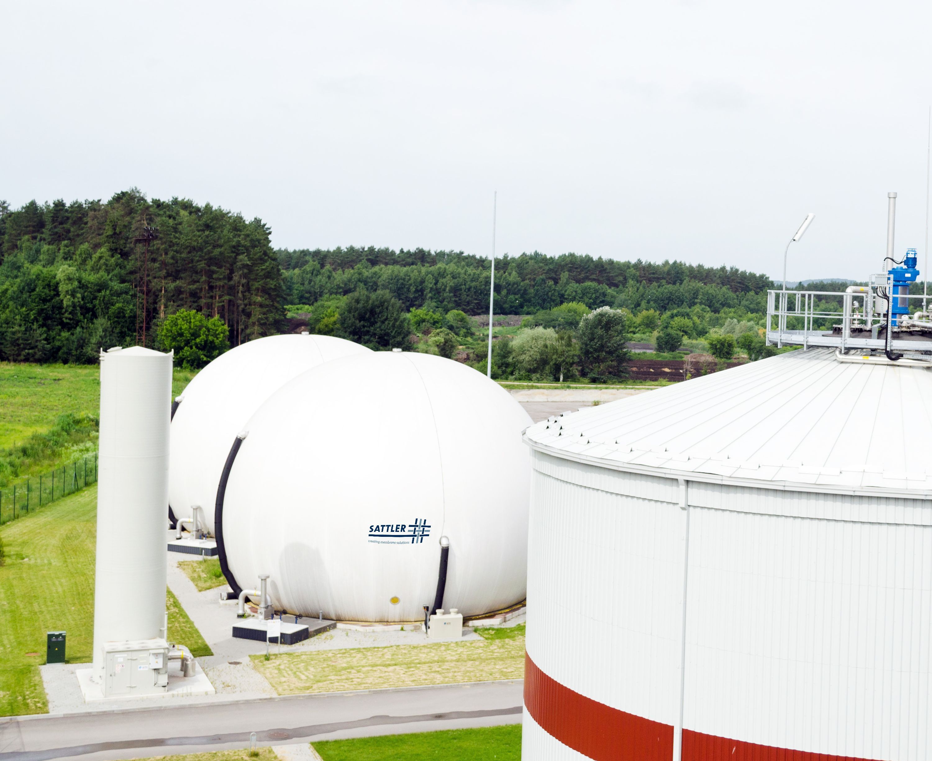 Zwei Doppelmembran-Gasspeicher umgeben von grüner Natur.