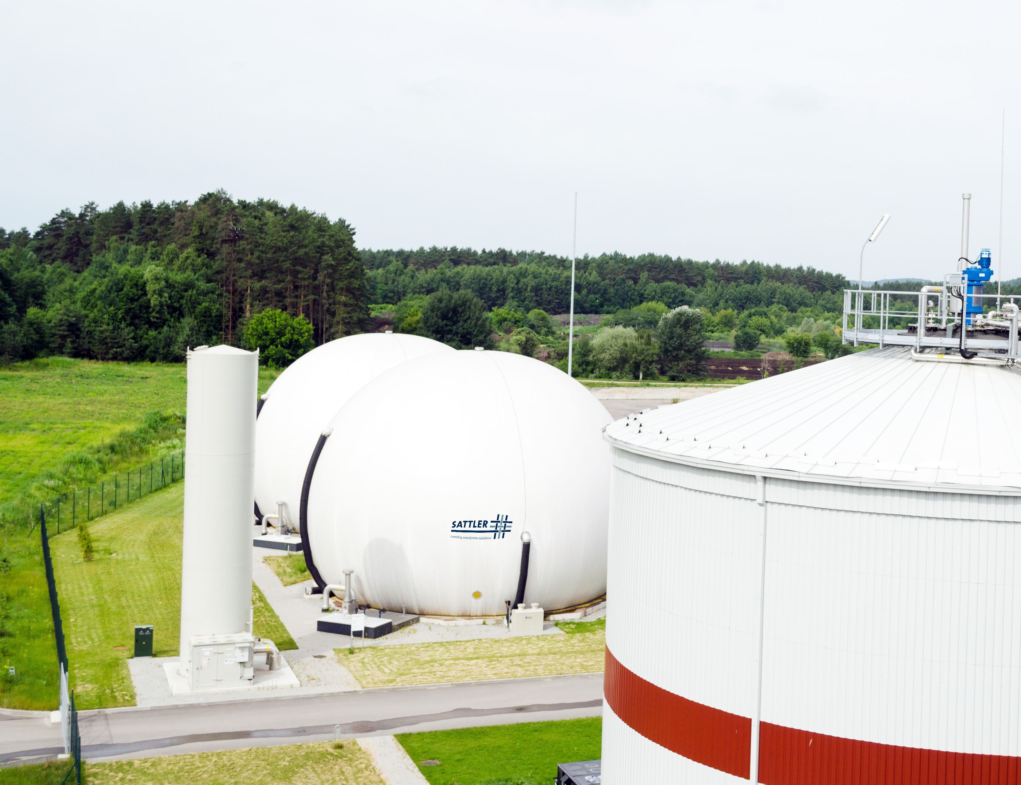 Deux réservoirs de gaz à double membrane entourés de nature verte.
